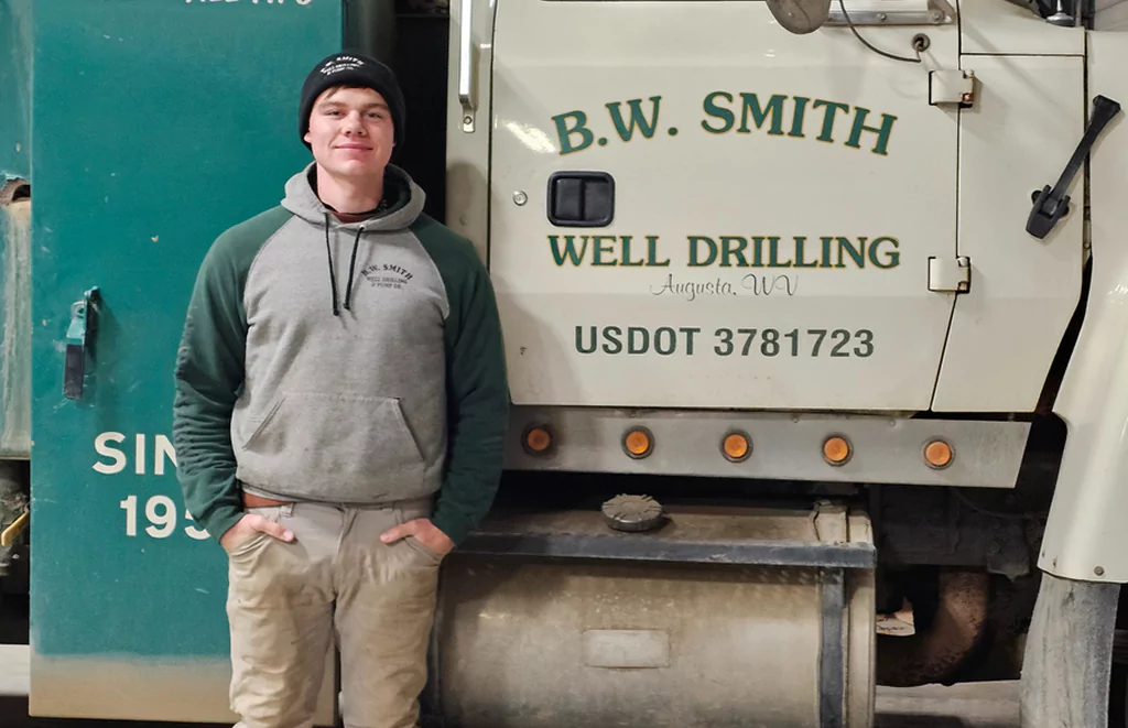 Water well drilling technician from B.W. Smith posing beside company truck in West Virginia